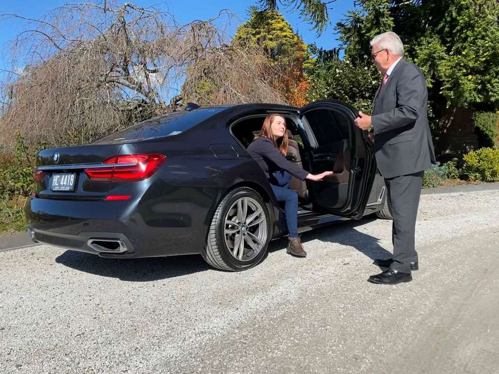 a man in a suit getting out of a car with a woman sitting in the back